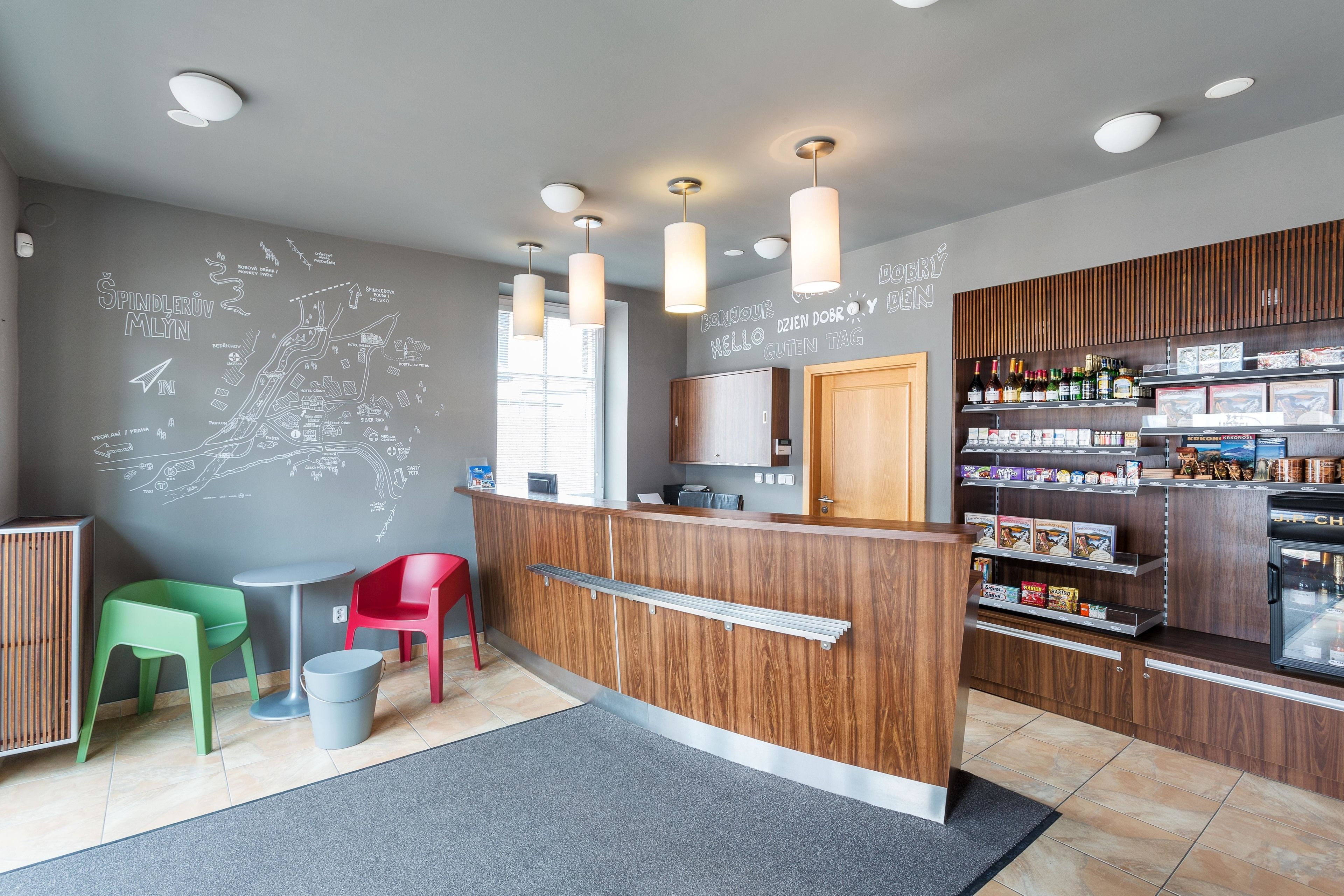 Een modern receptiegebied met een houten balie, een kaart aan de muur en een assortiment dranken en snacks op planken.