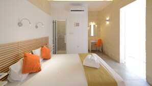 A hotel room with a bed, two pillows, a desk, a chair, and a bathroom door. - VBL Hostel – Adults only (Valletta)