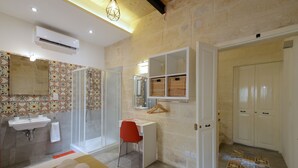A modern bathroom with a shower, sink, and a red chair. - VBL Hostel – Adults only (Valletta)