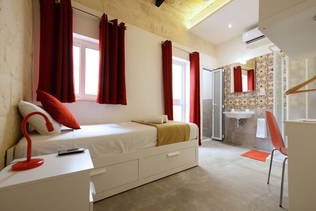 Ein modernes Schlafzimmer mit Bett, Nachttisch und einem Badezimmer mit Waschbecken und Dusche.