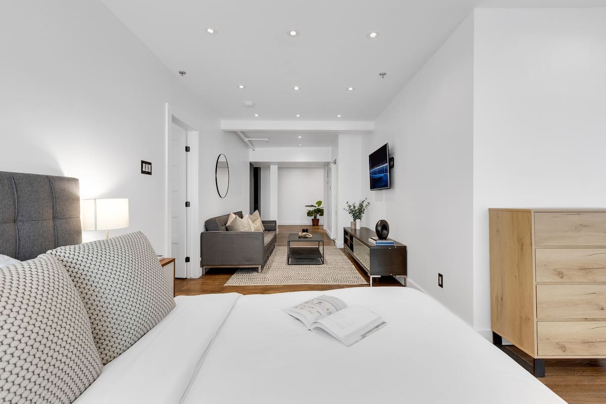 Una habitación de hotel moderna con una cama grande, un sofá, una mesa de centro y un televisor.