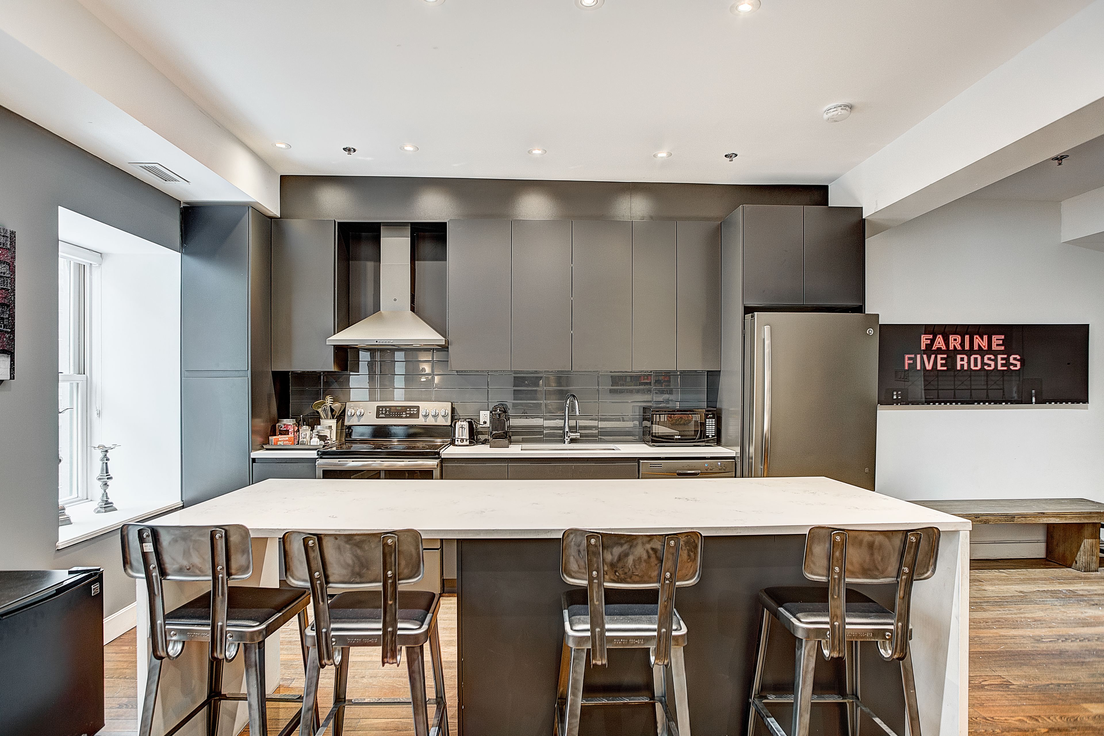 A modern kitchen with a central island, stainless steel appliances, and bar stools.