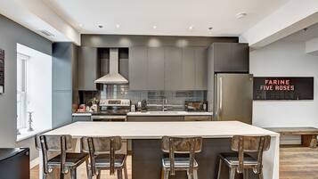 A modern kitchen with a central island, stainless steel appliances, and bar stools.