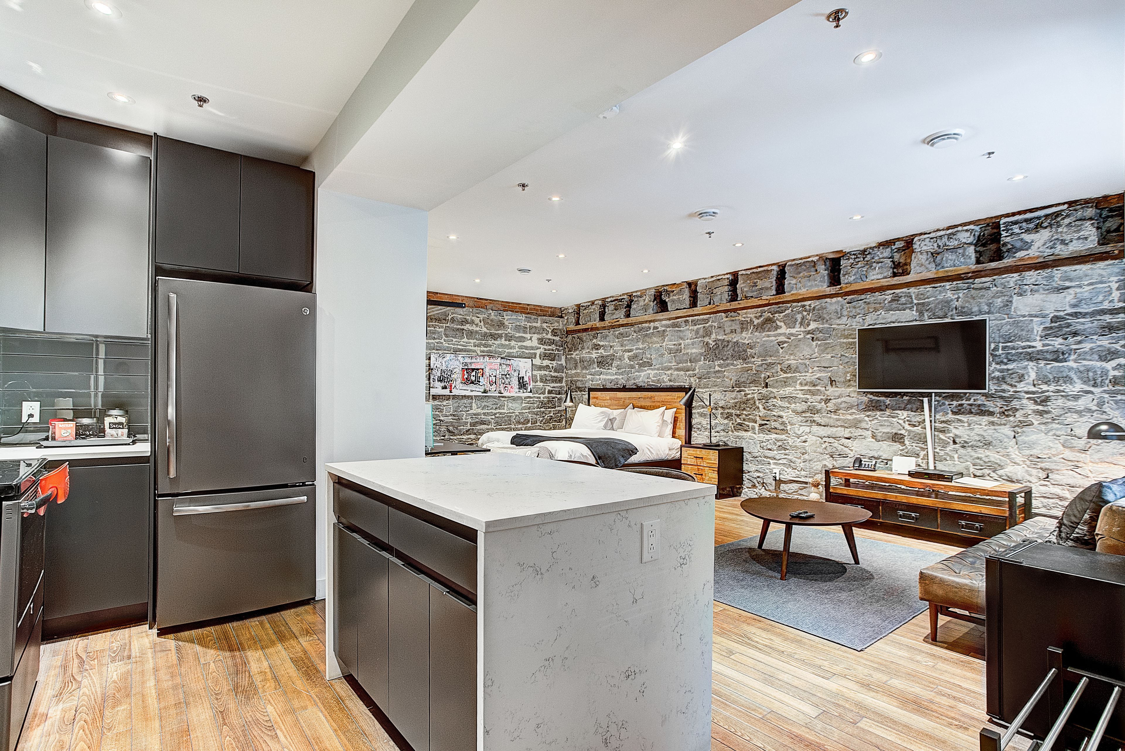 A modern kitchen with dark cabinets, a large island, and a stone accent wall.