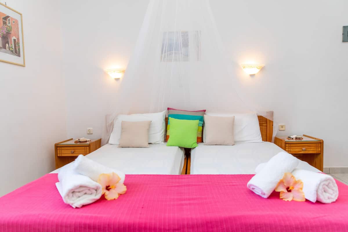 A double bed with a canopy, two bedside tables, and a wall-mounted light fixture.