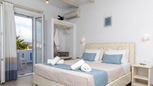 Une chambre à coucher avec un lit, une table de chevet, une lampe fixée au mur et une vue sur l’extérieur.
