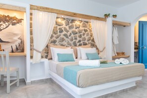 A bedroom with a stone headboard, white bedding, and a view of the sea through a window. - Arhontiko Studios (Naxos)