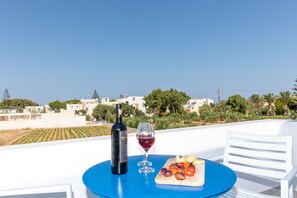 A table with a bottle of wine, a glass of red wine, and a board with grapes and cheese on a blue table. - Arhontiko Studios (Naxos)