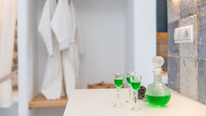 Une salle de bain avec un comptoir blanc, une bouteille verte et deux verres.