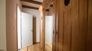 A hallway with wooden flooring, a large wooden wardrobe with a mirror, and a white door at the end. - Landhaus Schulze Osthoff (Warendorf)