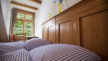 A bedroom with a wooden headboard, a window with curtains, and striped bedding.