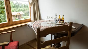 Una mesa de comedor con mantel, dos botellas de cerveza y un vaso sobre un posavasos.