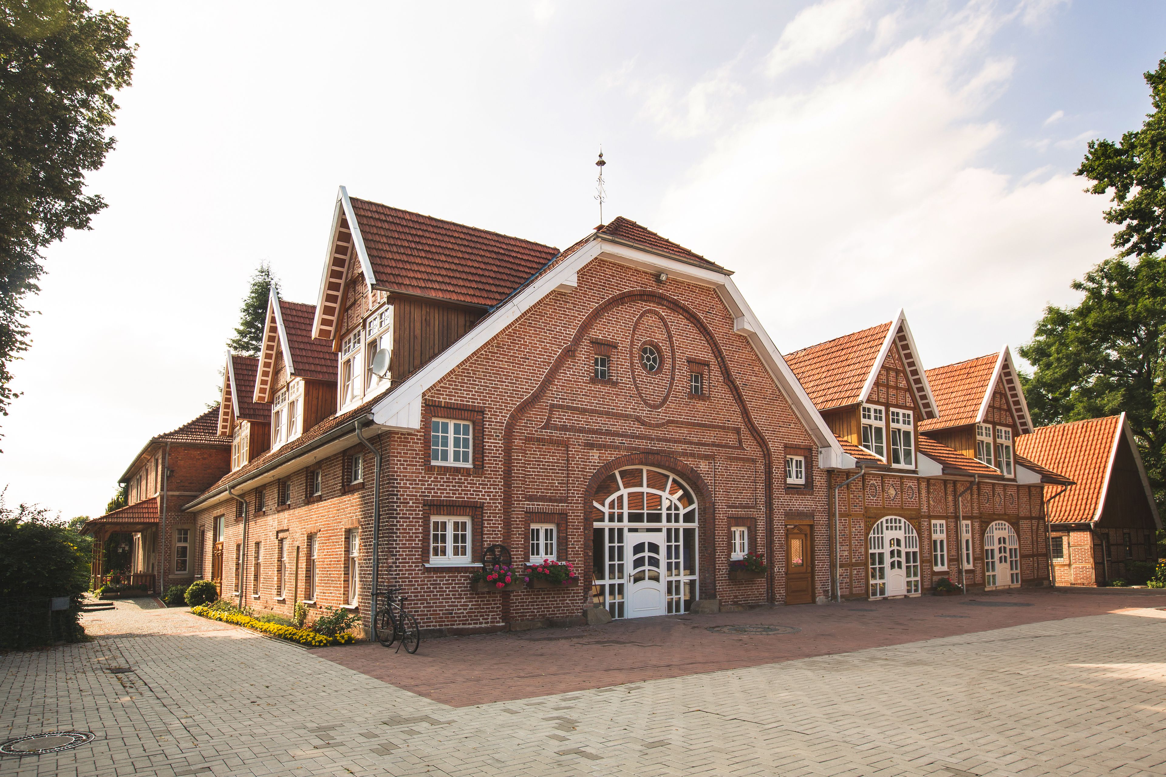 En stor murstensbygning med en symmetrisk facade, mange vinduer og en central indgang med en dekorativ bue.