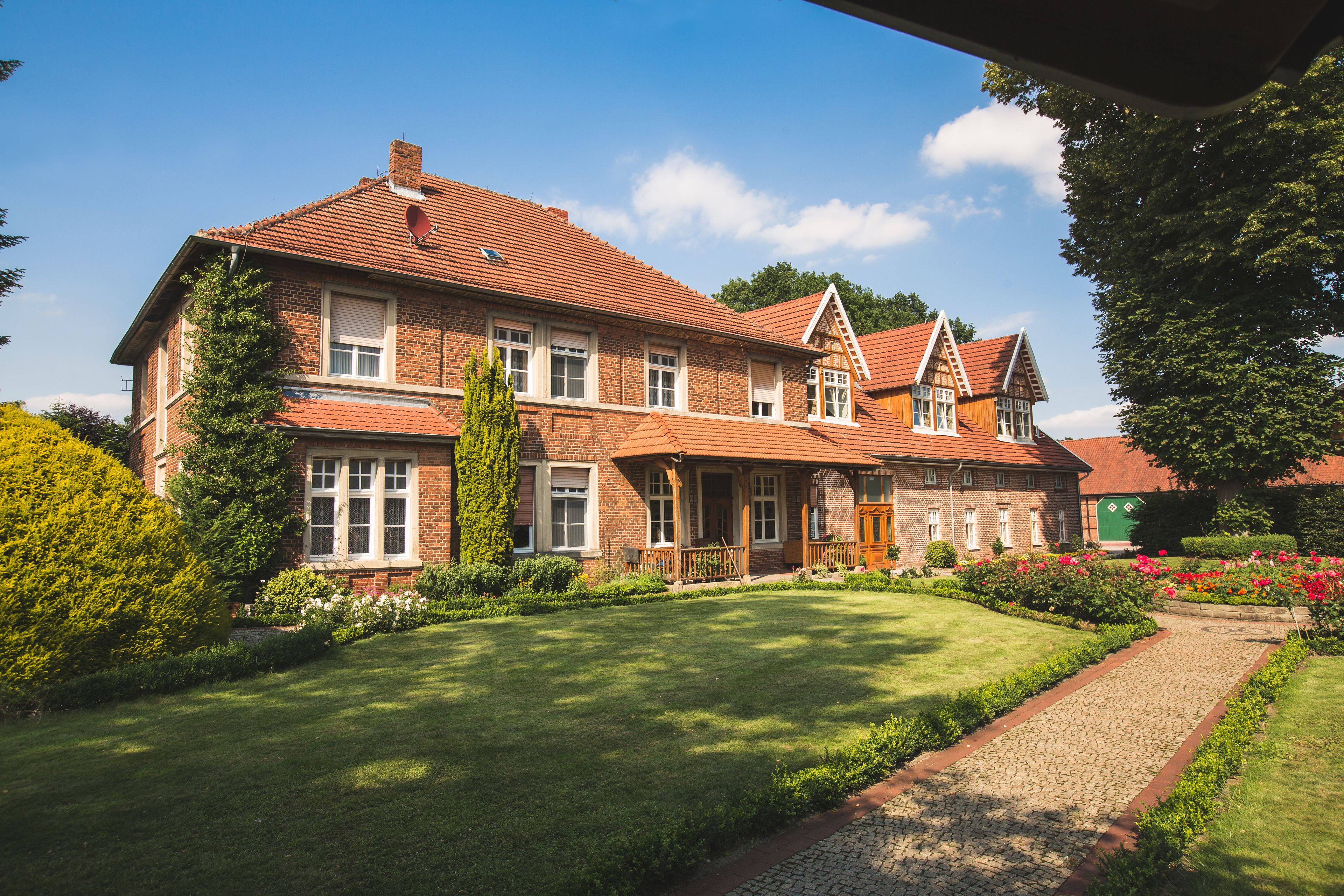A large brick house with a well-maintained lawn and a cobblestone pathway.