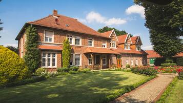A large brick house with a well-maintained lawn and a cobblestone pathway.