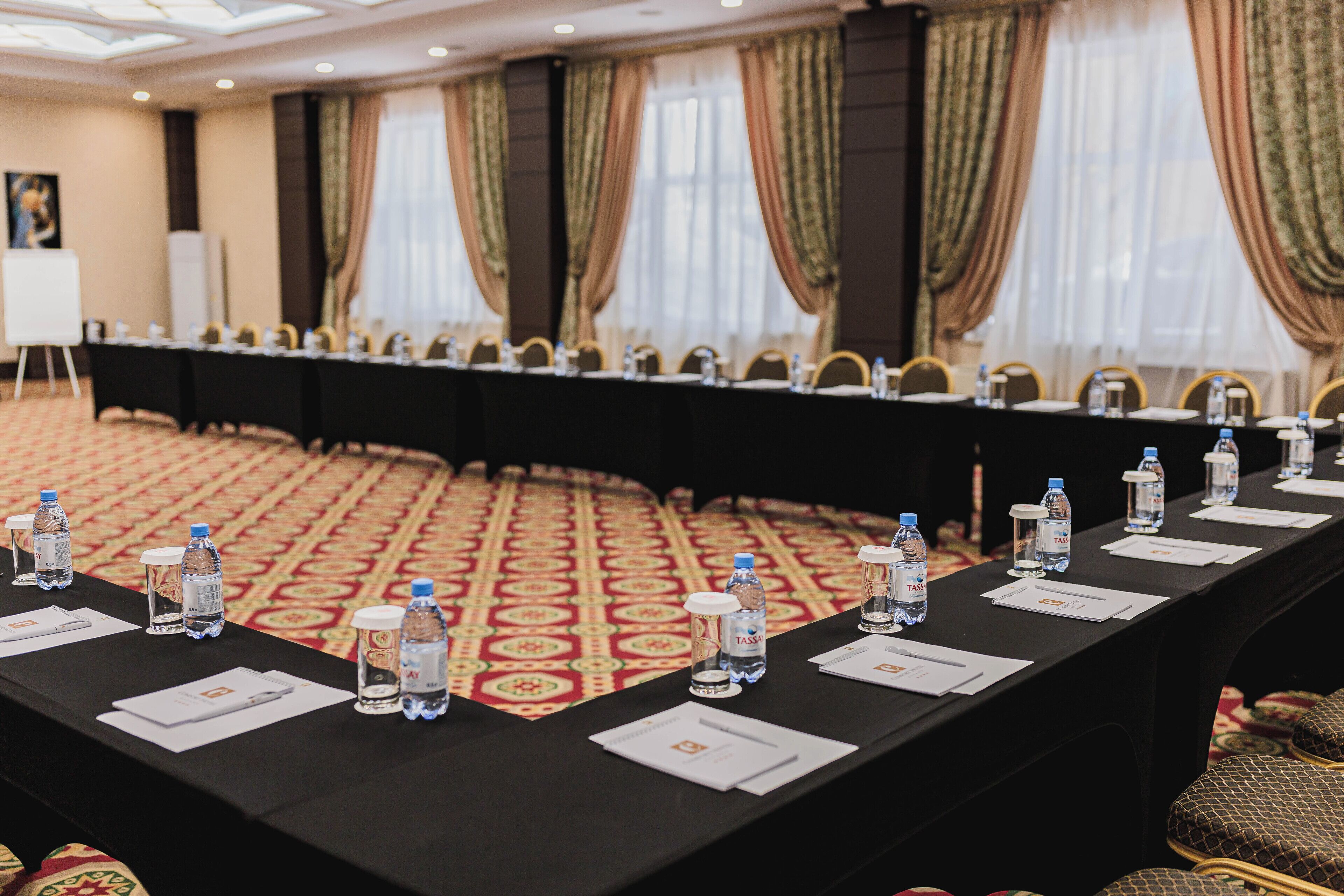 Une salle de conférence avec une longue table préparée pour les réunions, équipée de bouteilles d’eau et de blocs-notes.