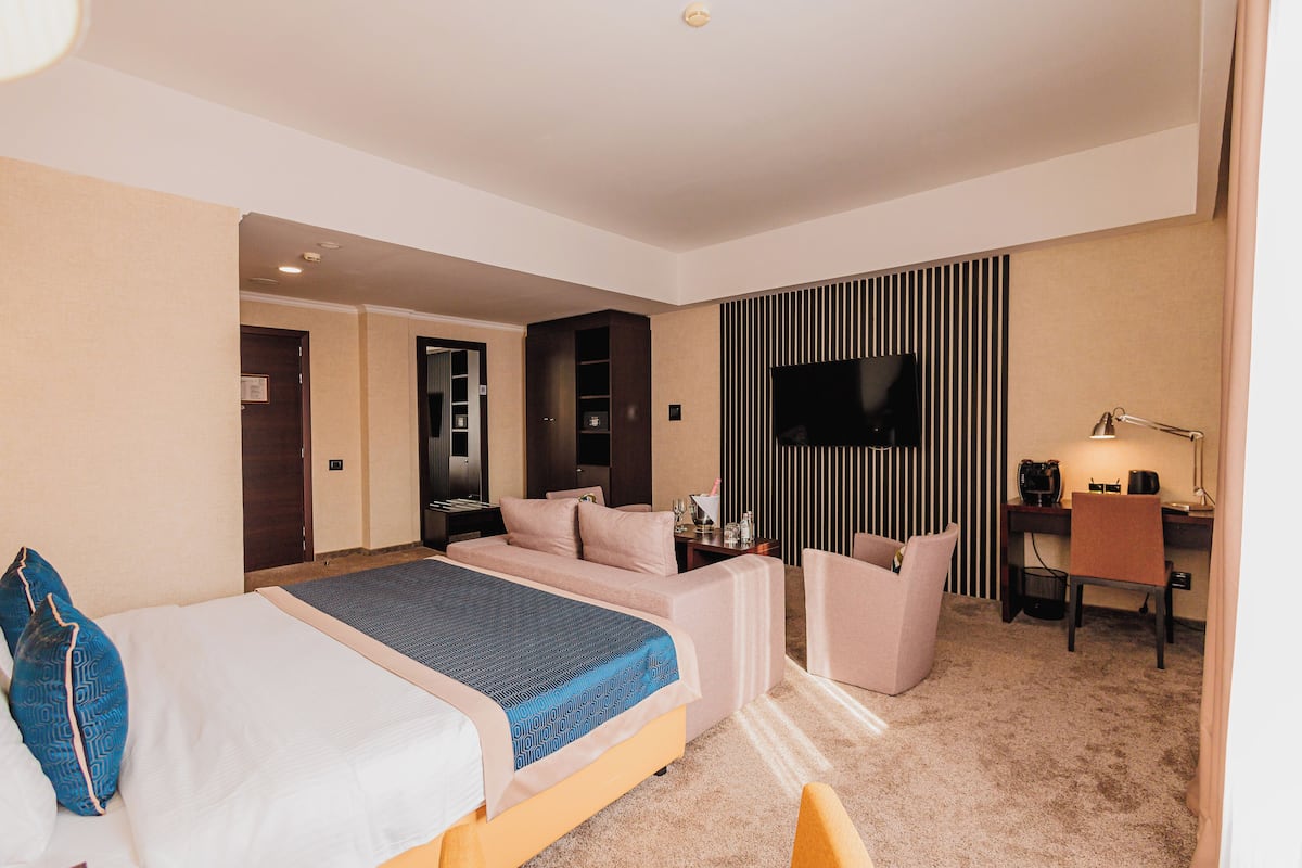 Een hotelkamer met een bed, een bureau, een stoel, een televisie en een minibar.
