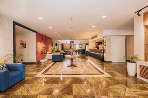 Vestíbulo de hotel con una recepción, zona de estar y una gran mesa decorativa.