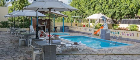 Una piscina al aire libre, sombrillas, sillones reclinables de piscina