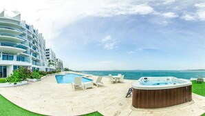 A hotel with a pool, hot tub, and lounge chairs with a view of the ocean. - Naos Luxury Rents (Panama City)