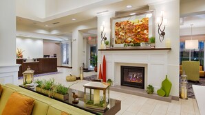 A spacious lobby with a fireplace, a reception desk, and a seating area with a sofa and coffee table. - Hilton Garden Inn Salina (Salina)