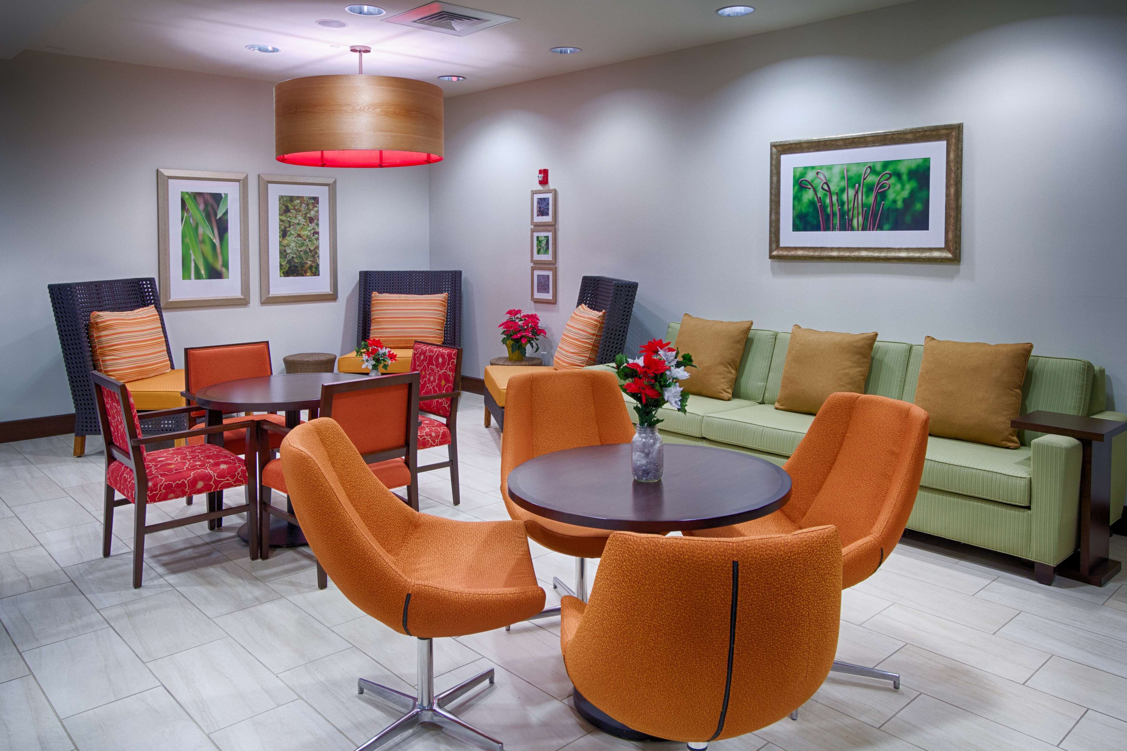 A modern dining area with a round table, orange chairs, and a green sofa.