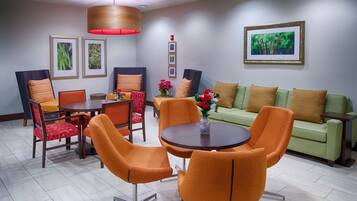 A modern dining area with a round table, orange chairs, and a green sofa.