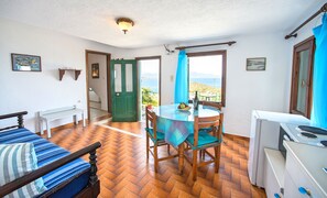 Une chambre avec un lit, une table et des chaises, un petit coin cuisine et une vue sur la mer.