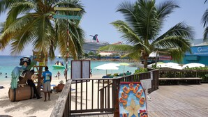A beachside area with a wooden deck, palm trees, and beach umbrellas. - Ocho Rios Getaway Villa at The Palms (Ocho Rios)