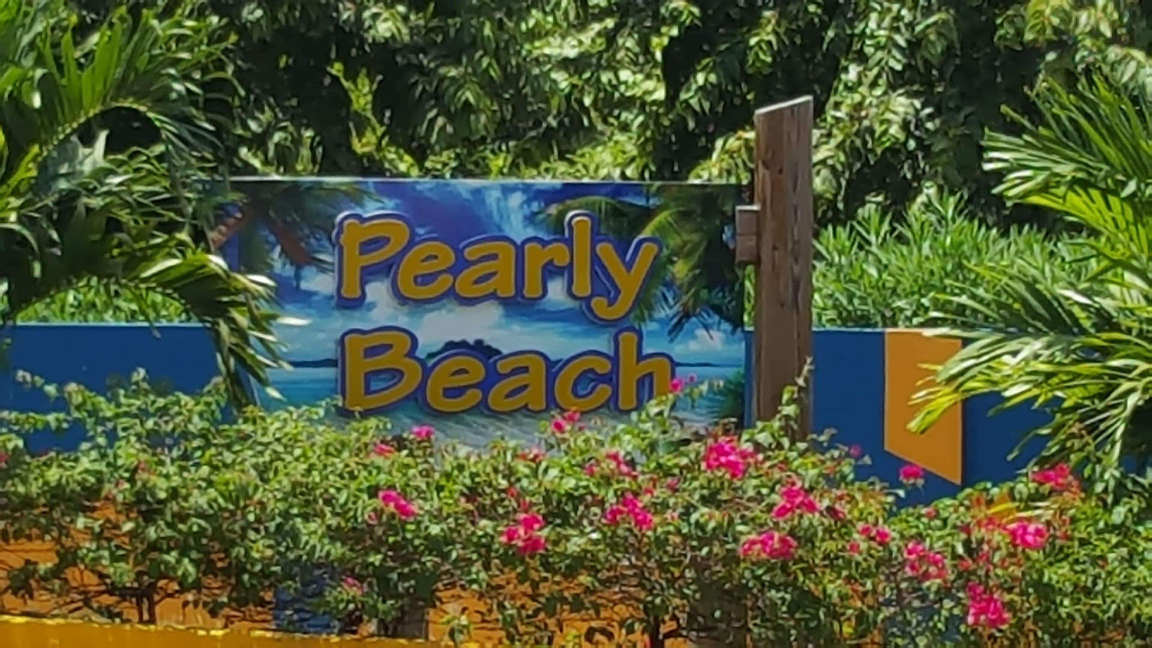 A sign for Pearly Beach with a tropical background.