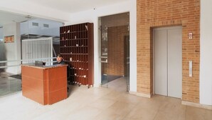 A reception area with a wooden desk, a metal security gate, and a brick wall. - Studio Chapinero 216 (Bogotá)