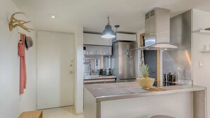 Uma cozinha moderna com eletrodomésticos de aço inoxidável, uma ilha central com bancos e uma luminária pendente.
