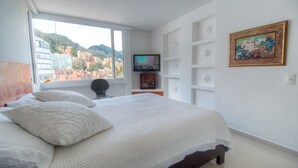 A bedroom with a large bed, a TV on a stand, and a painting on the wall. - Apartment Zona Rosa 2204 (Bogotá)