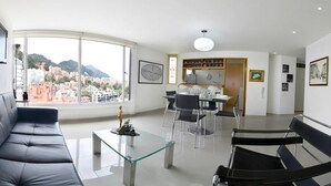 A modern living room with a sofa, a glass coffee table, and a dining area with chairs and a table. - Apartment Zona Rosa 2204 (Bogotá)