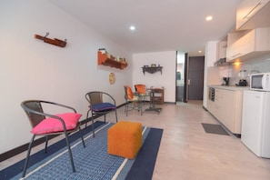 Ein modernes Wohnzimmer mit Essbereich, Küche und einem kleinen Balkon.