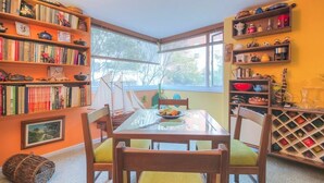 A dining area with a glass table, wooden chairs, and a bookshelf filled with books and decorative items. - Apartment Chapinero 404 (Bogotá)