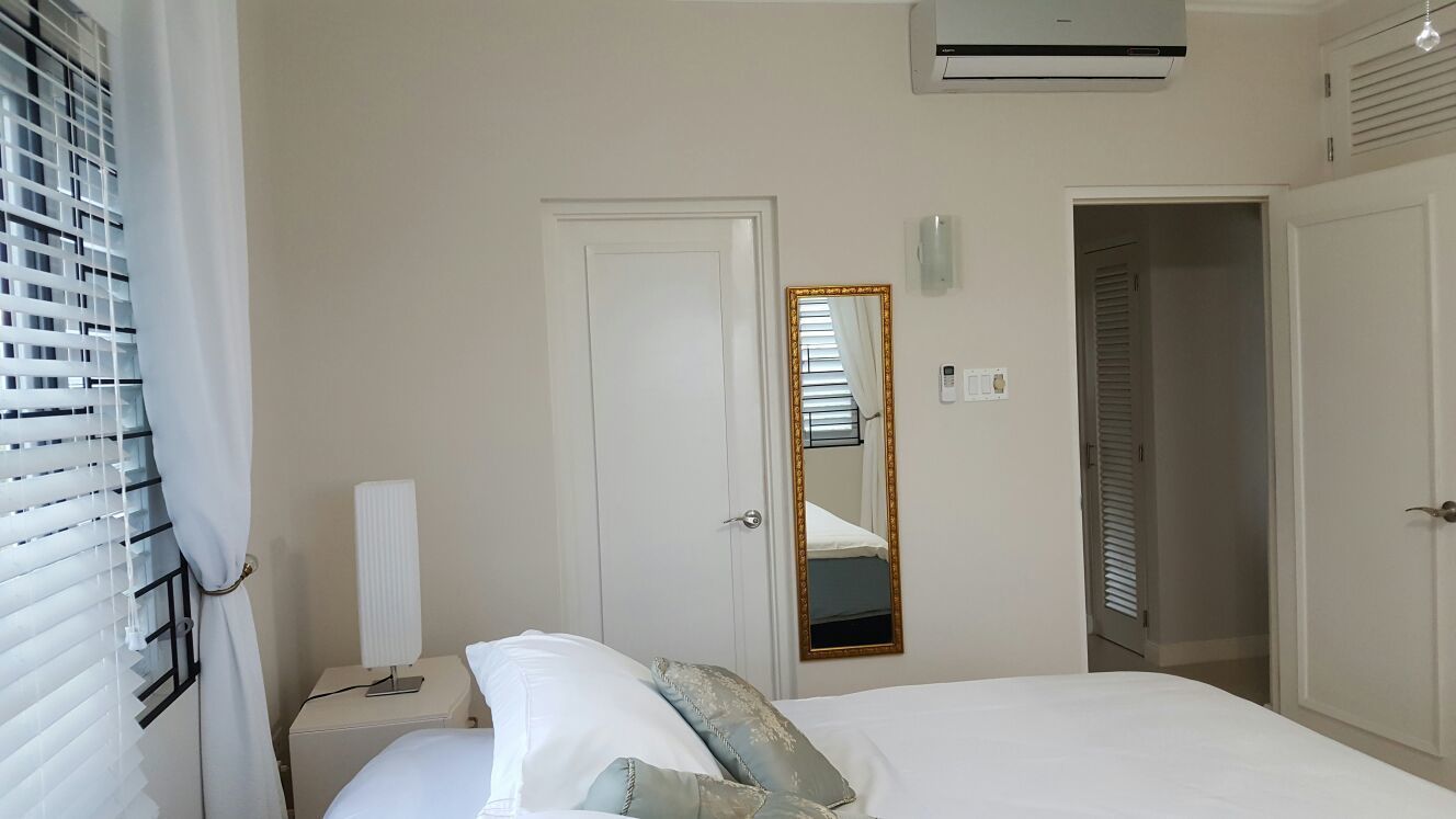 A bedroom with a bed, a bedside table, a lamp, a mirror, and a wardrobe.