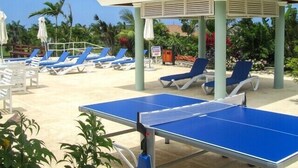 Ein Strandloungebereich mit blauen Liegestühlen und einem Tischtennis-Tisch.