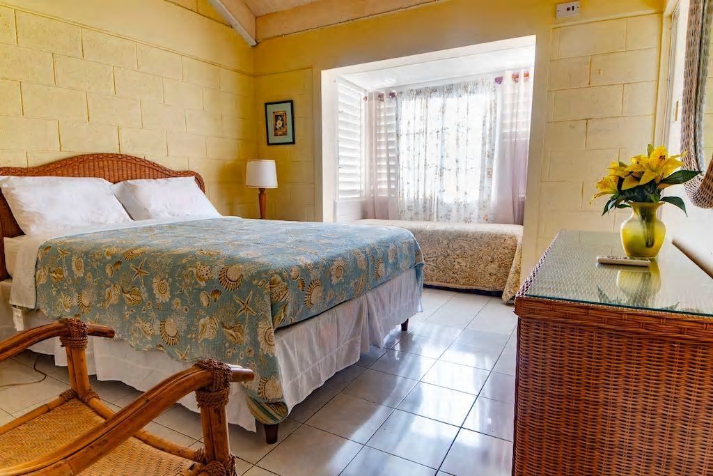 A room with a bed, a chair, a table, and a window with curtains.