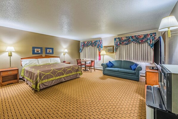 A hotel room with a bed, a sofa, a desk, and a television.