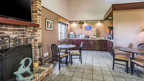 A restaurant with a brick fireplace, a flat-screen TV, and a bar area. - Rodeway Inn Saint Joseph (St. Joseph)