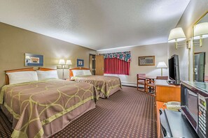 A hotel room with two beds, a desk with a computer, a TV, and a mirror.