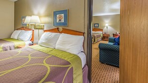 A hotel room with two beds, a sitting area with a chair, and a small table. - Rodeway Inn Saint Joseph (St. Joseph)