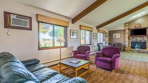 A living room with a blue leather sofa, two purple armchairs, a wooden coffee table, and a fireplace. - Rodeway Inn Saint Joseph (St. Joseph)