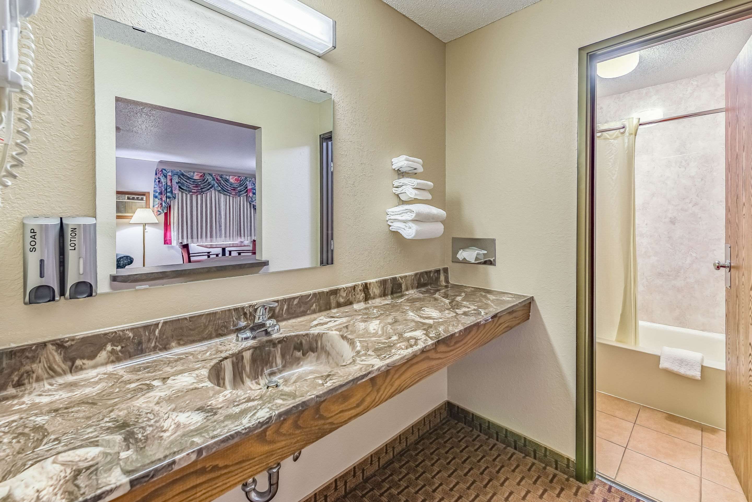A bathroom with a marble sink, a mirror, a towel rack, and a shower area.
