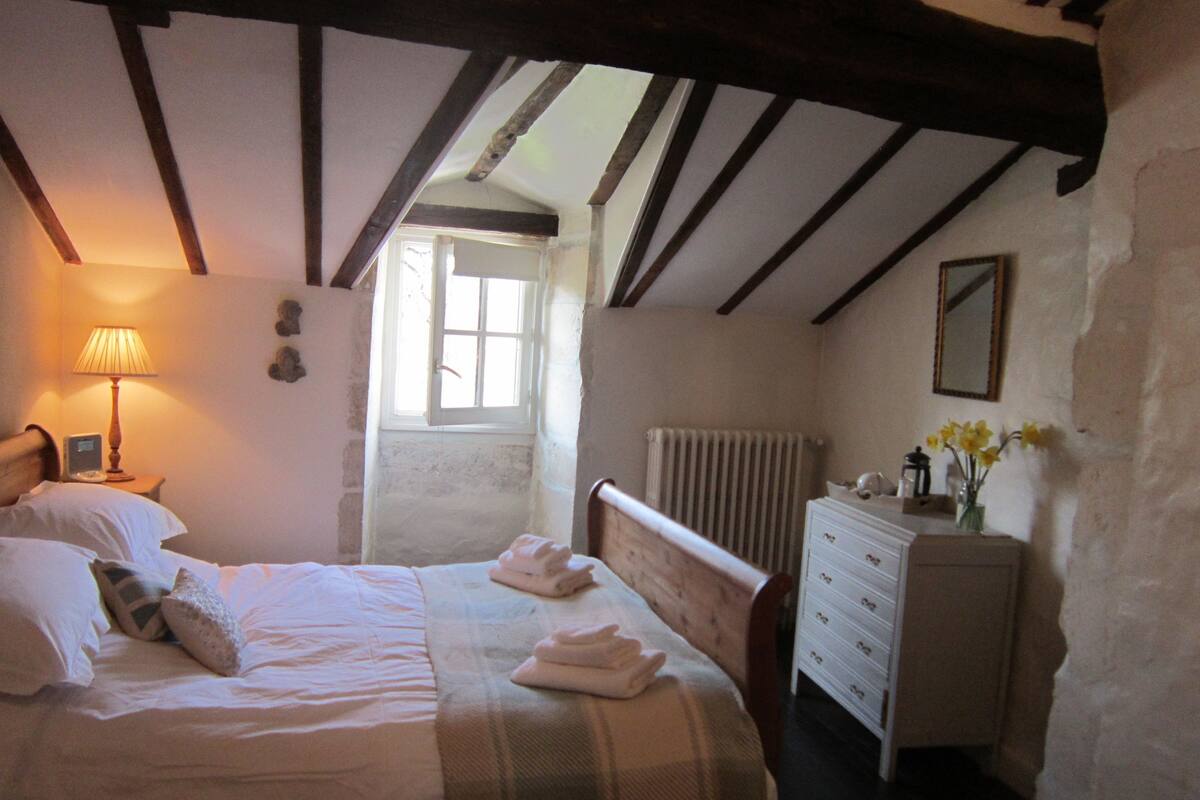 Une chambre à coucher avec un lit, une lampe de chevet, une commode et une fenêtre.