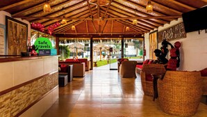 A reception area with a wooden ceiling, wicker furniture, and a 'Safe travels' sign. - QALA Hotel & Resorts (Grocio Prado)