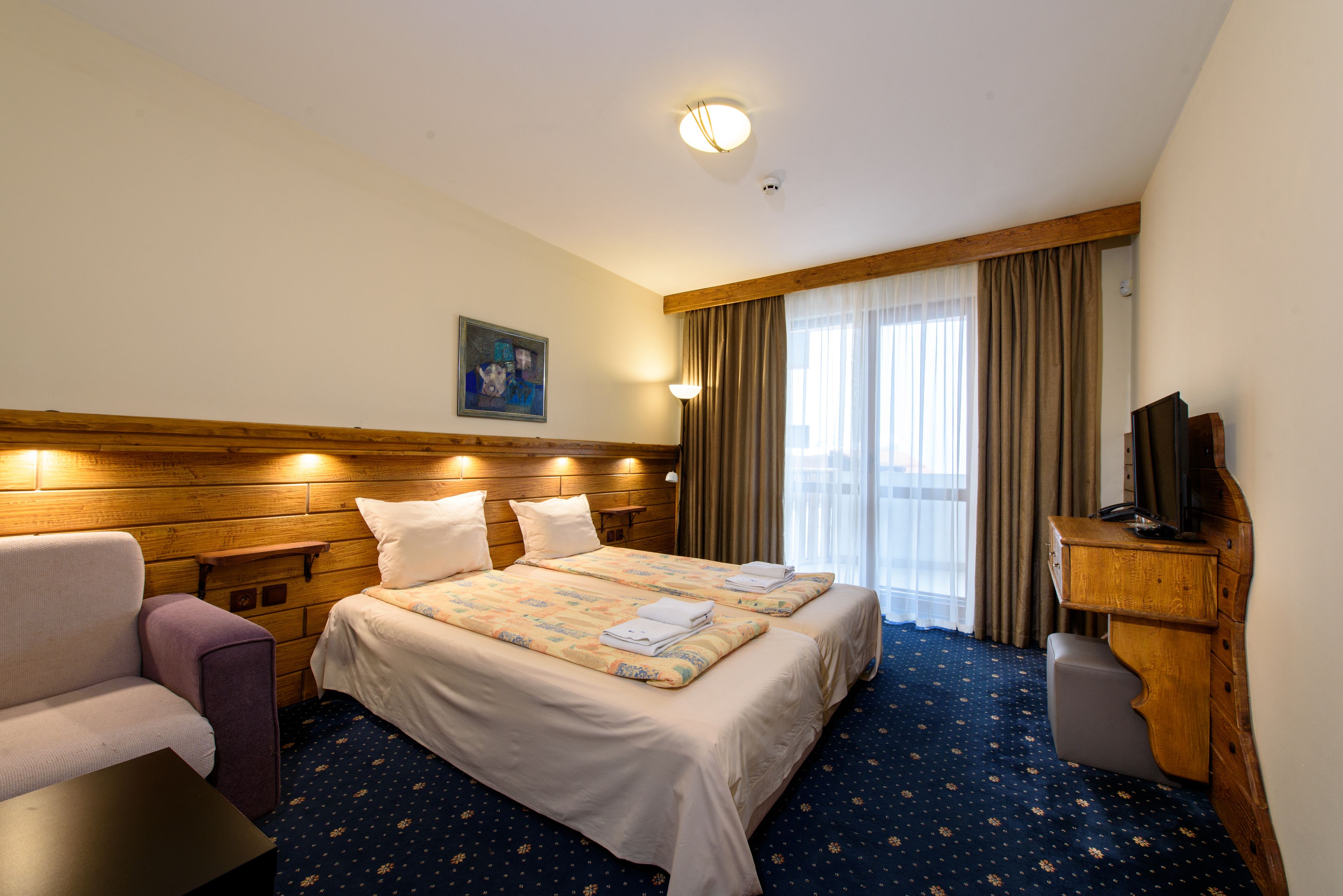 Habitación de hotel con una cama grande, un sofá, un escritorio y una televisión.