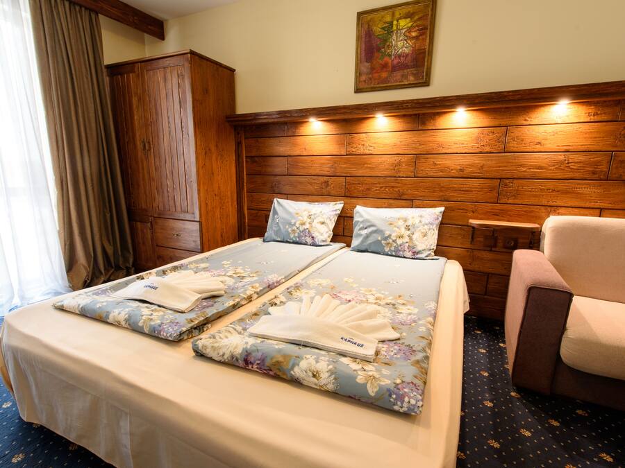 Una camera d'hotel con una testiera in legno, un letto con biancheria da letto floreale, una sedia e un armadio.
