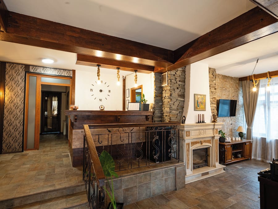 Un salón amplio con chimenea, pared de piedra y vigas de madera.
